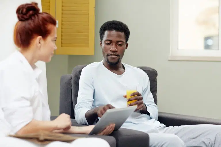 Man holding juice and tablet talking with woman
