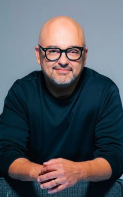 Smiling bald man wearing glasses, dark sweater