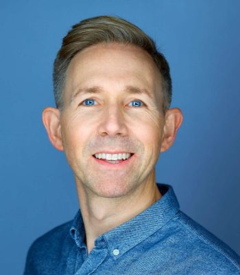 Smiling man wearing blue shirt, blue background